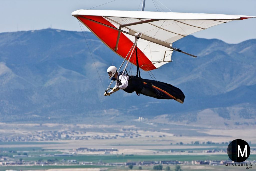 man hang gliding over a town