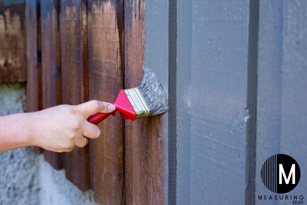 brush painting a wooden fence