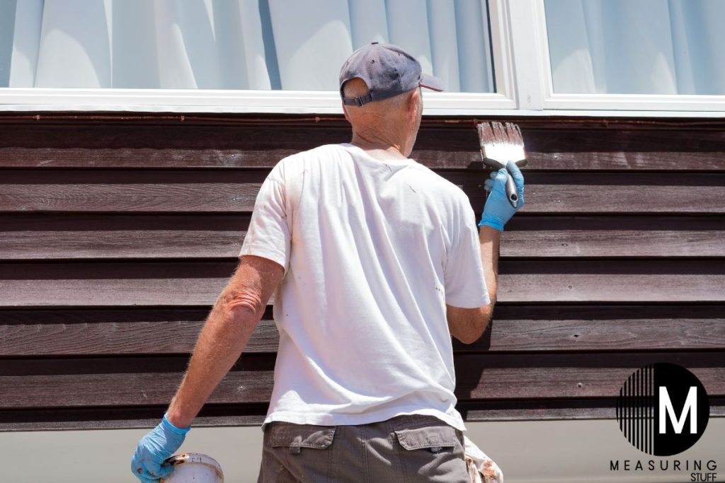 man painting under a house window