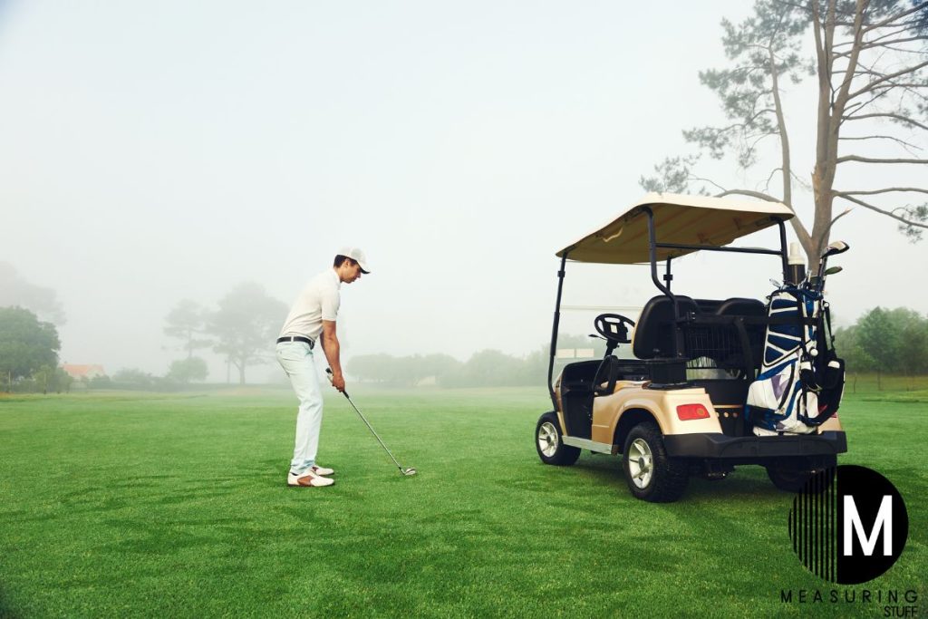 man playing golf next to a golf cart