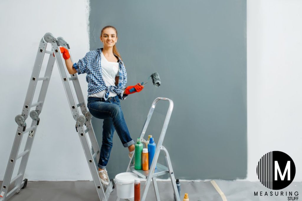 woman on a ladder holding a paint roller