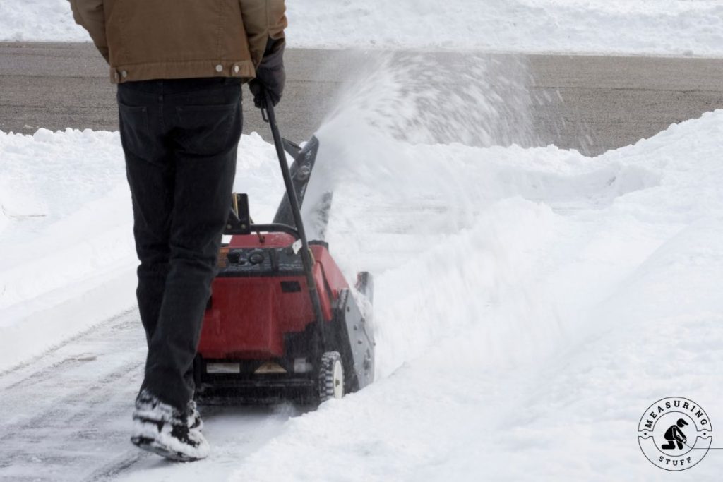 man using a snowblower in driveway