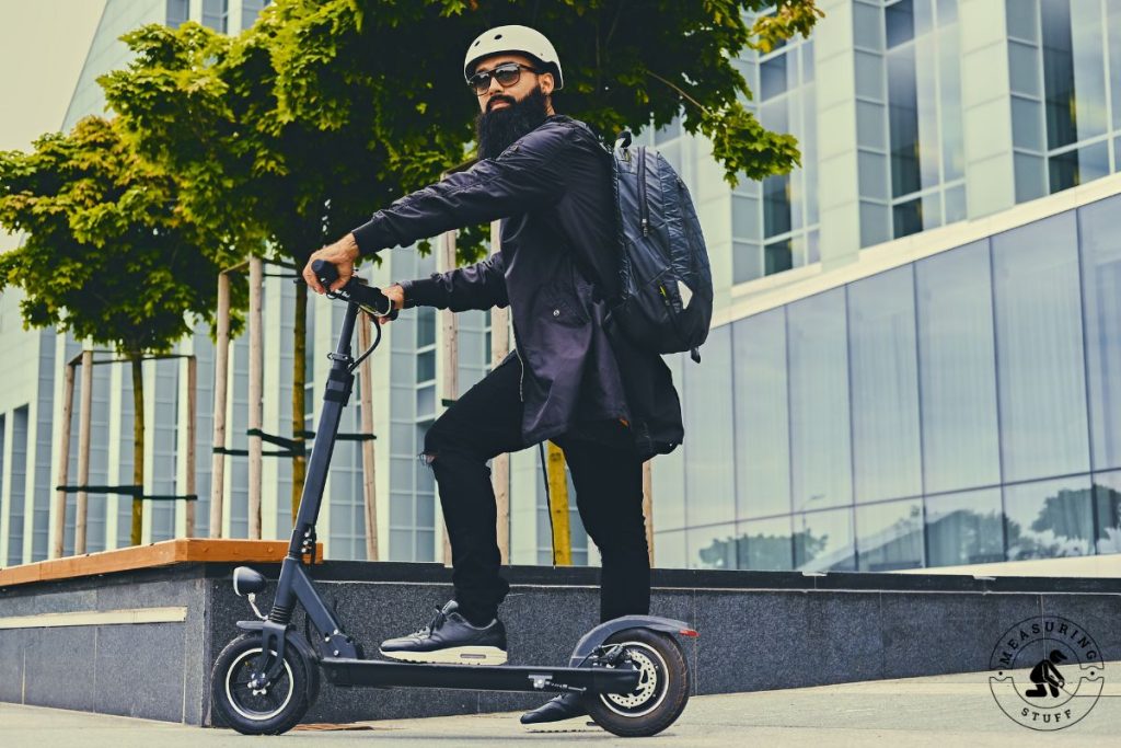 man riding an electric scooter wearing a backpack