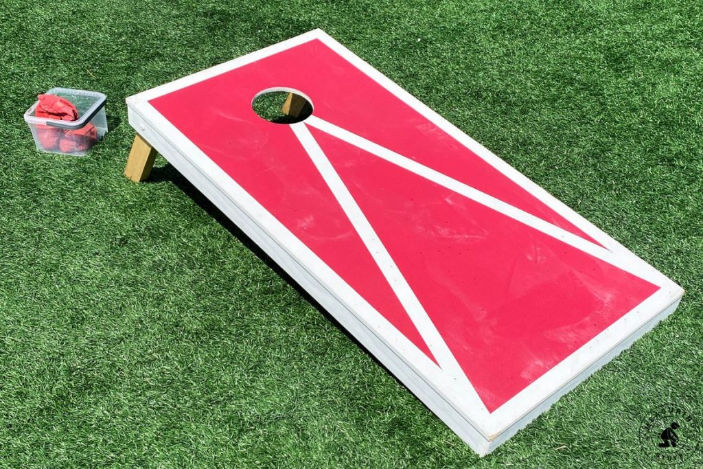 red and white cornhole board on grass