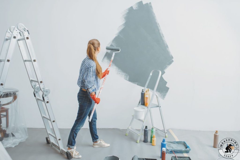 woman painting a wall with a paint roller