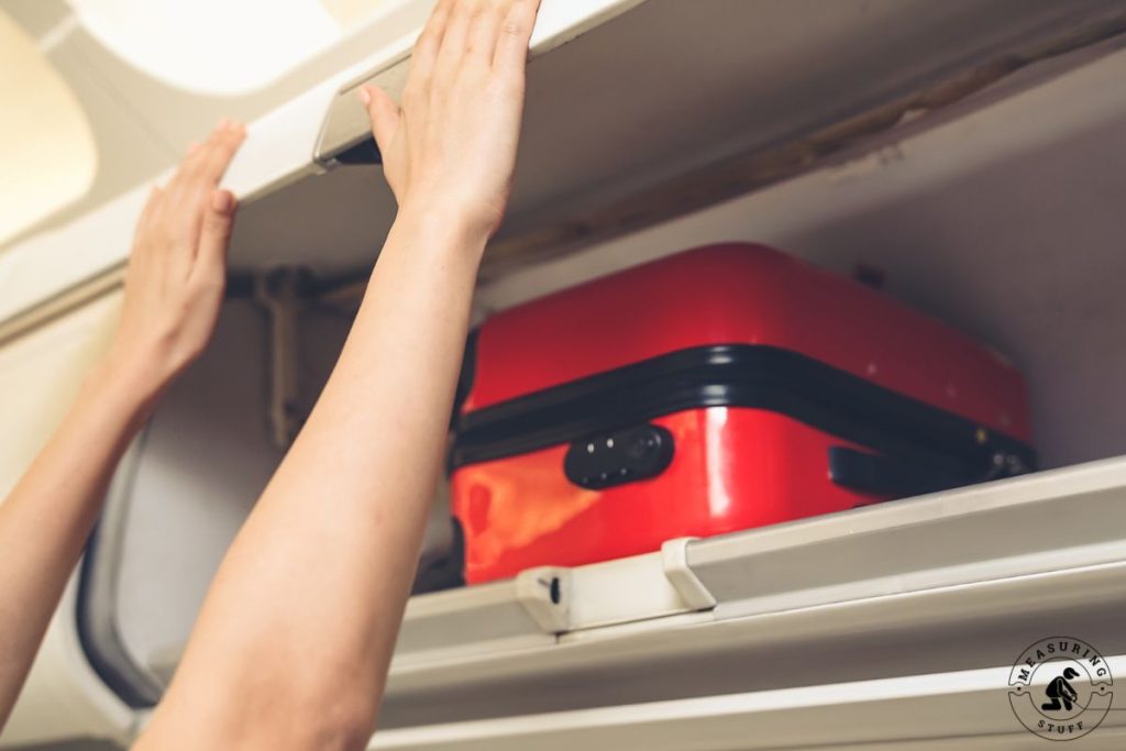 placing a suitcase in airplane overhead bin