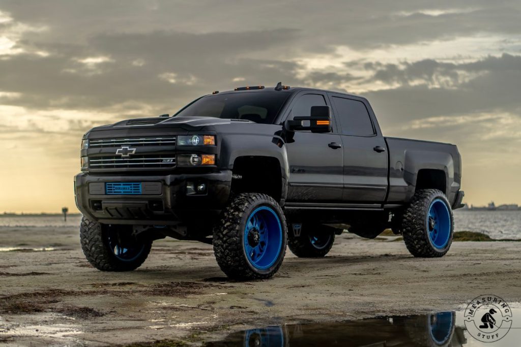 pickup truck on sand next to a lake