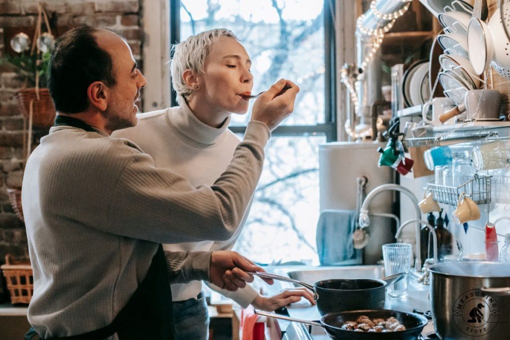couple tasting food in a kitchen