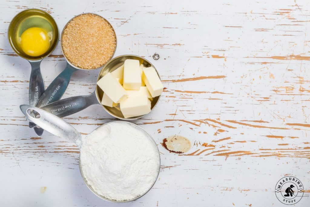 measuring cups filled with flour, butter, eggs, crumbs