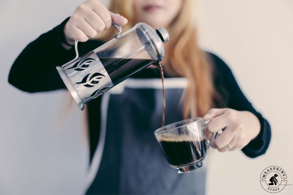 woman pouring coffee into a clear mug