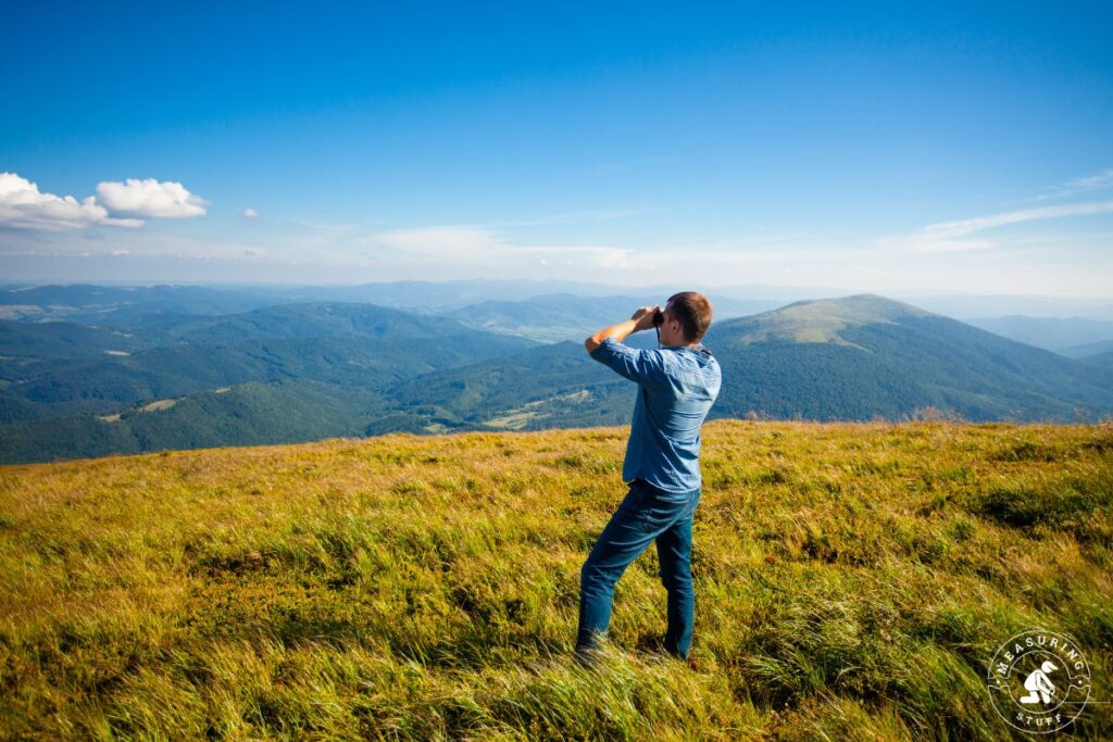 man looking through binoculars on a mountain