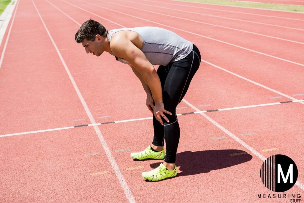 man leaning over on a running track