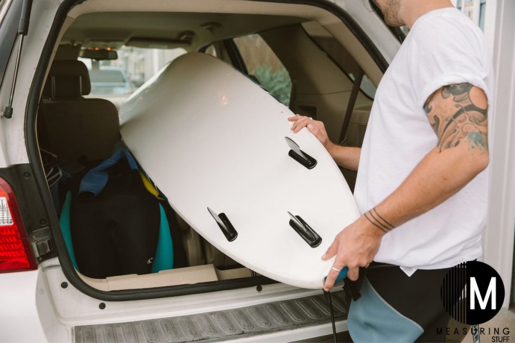 man loading a surfboard into a car