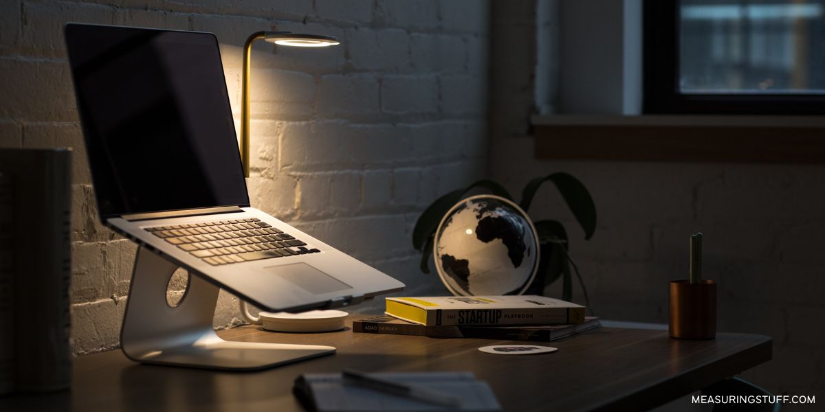 open laptop next to a globe and lamp