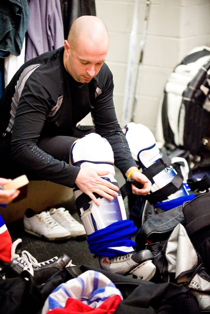 ice hockey player putting on shin guards