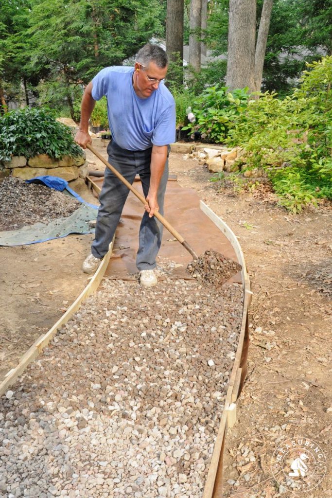 man shovelling gravel on a path