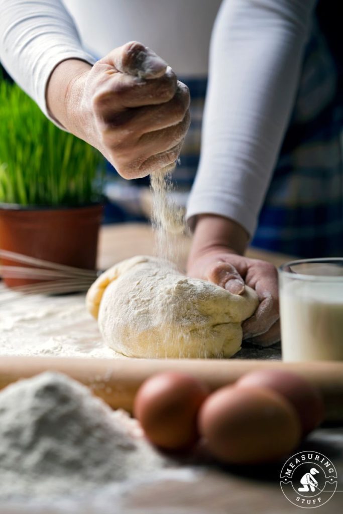 pouring flour on dough to make bread