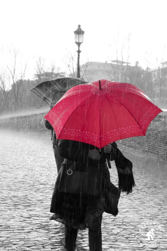 standing in rain with a red umbrella
