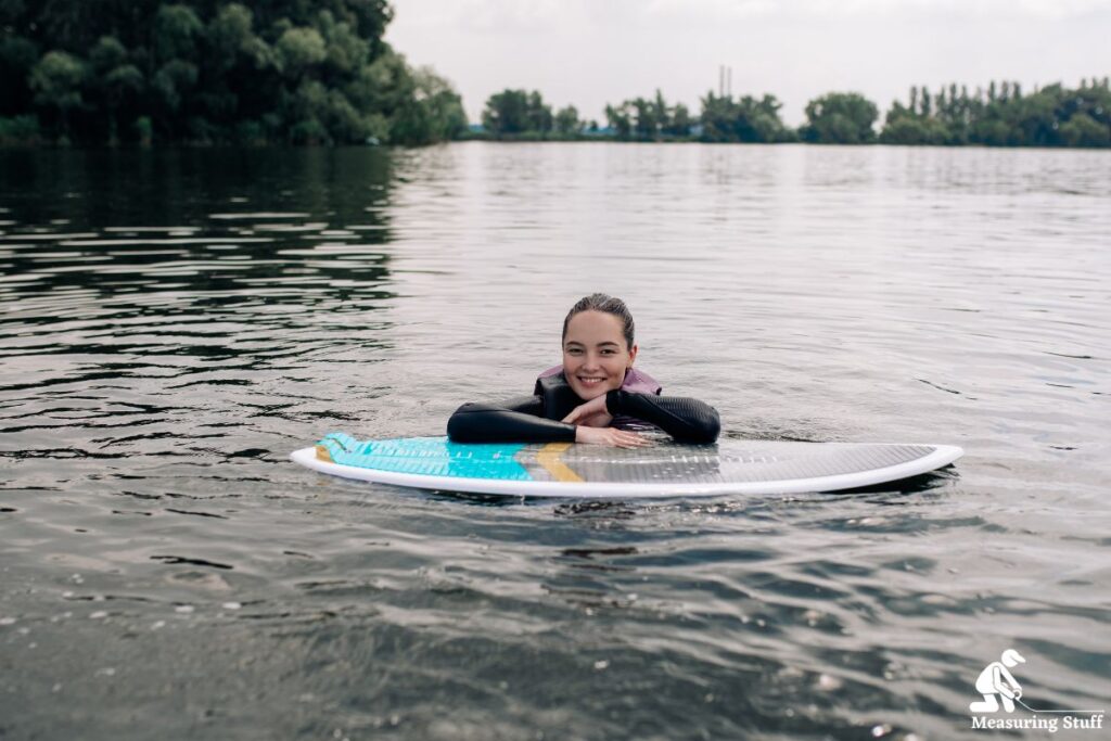 girl leaning on a wakesurf board in the water