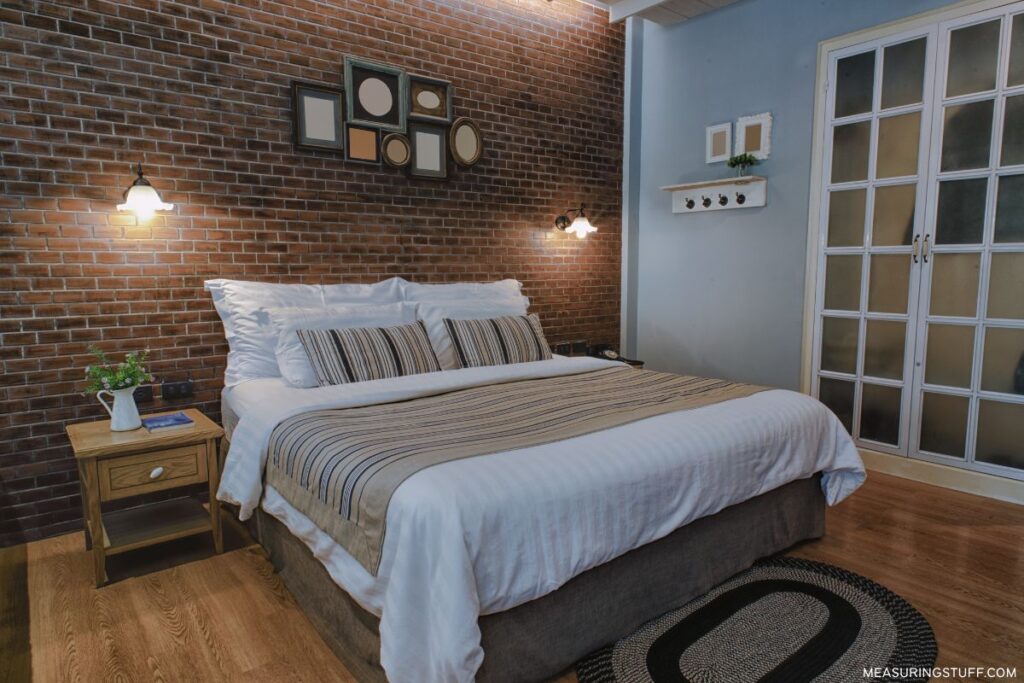 king sized bed next to a brick wall