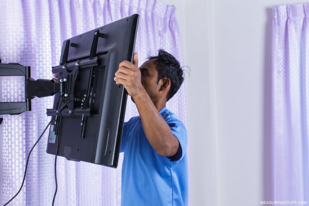 man wall mounting a tv