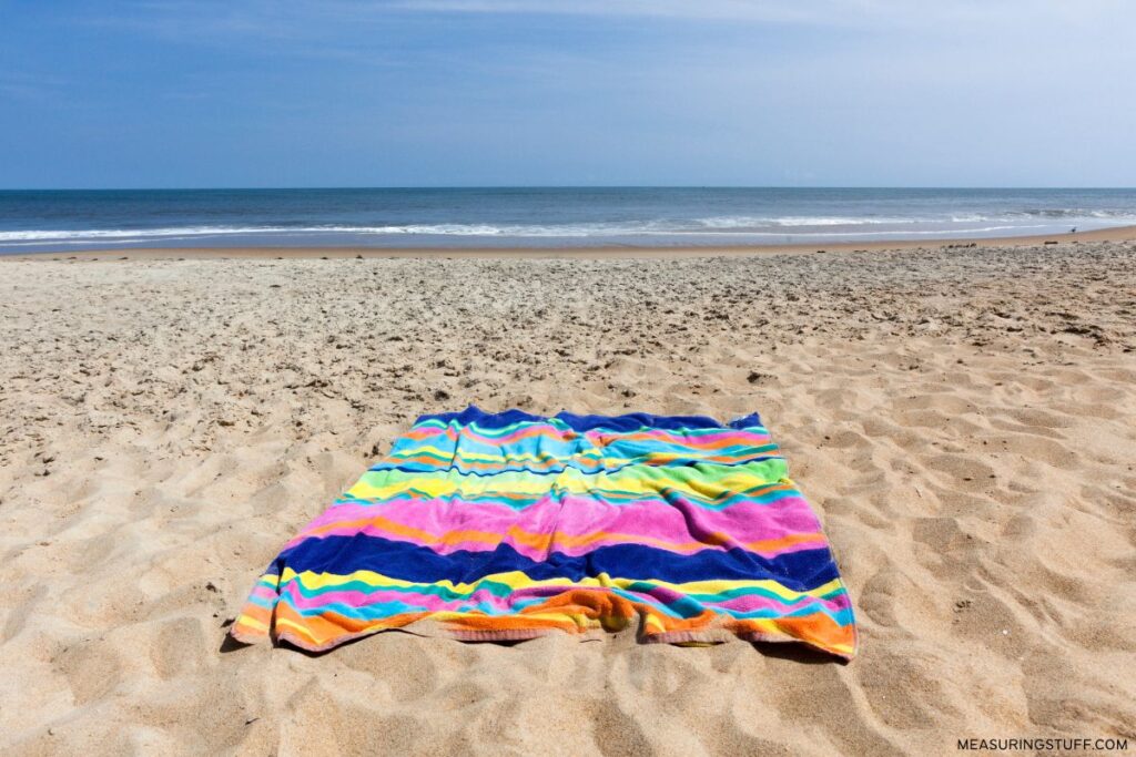 multi colored beach towel on sandy beach
