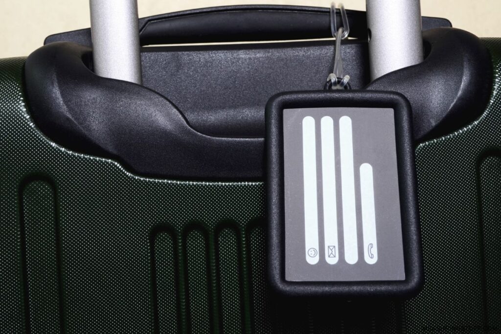 plastic luggage tag attached to handle of hardshell roller case