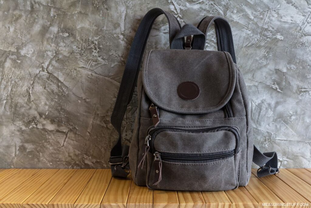canvas backpack against a marble wall