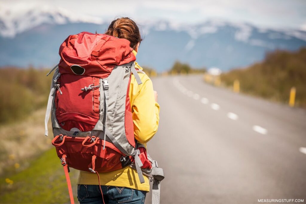 woman standing next to a highway wearing a large backpack