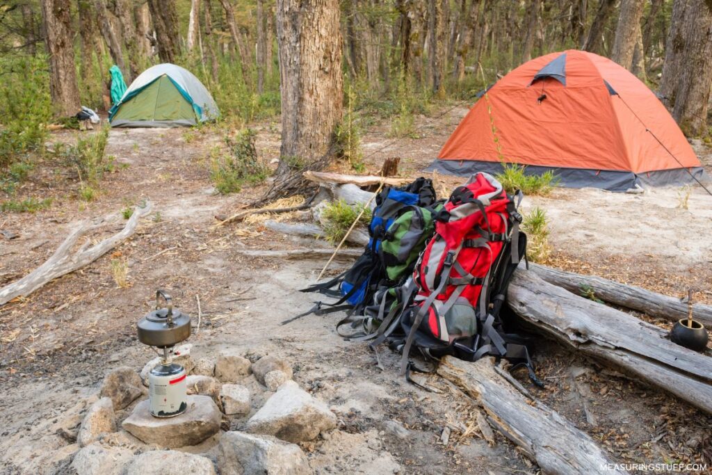 camping backpacks next to tents at a campsite