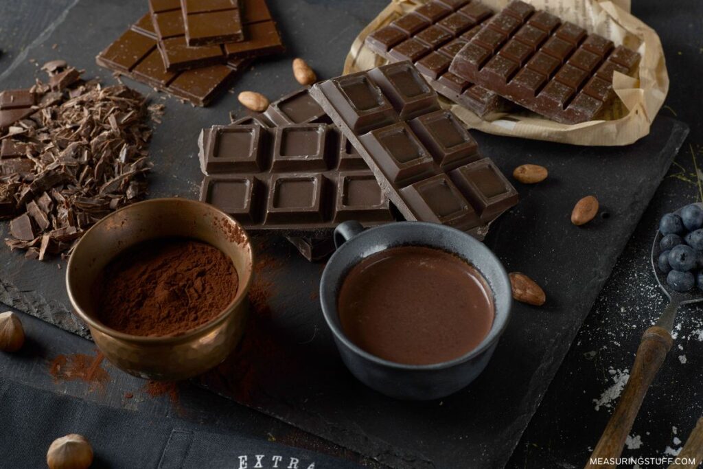 dark chocolate bars with bowls of dry chocolate powder and melted chocolate