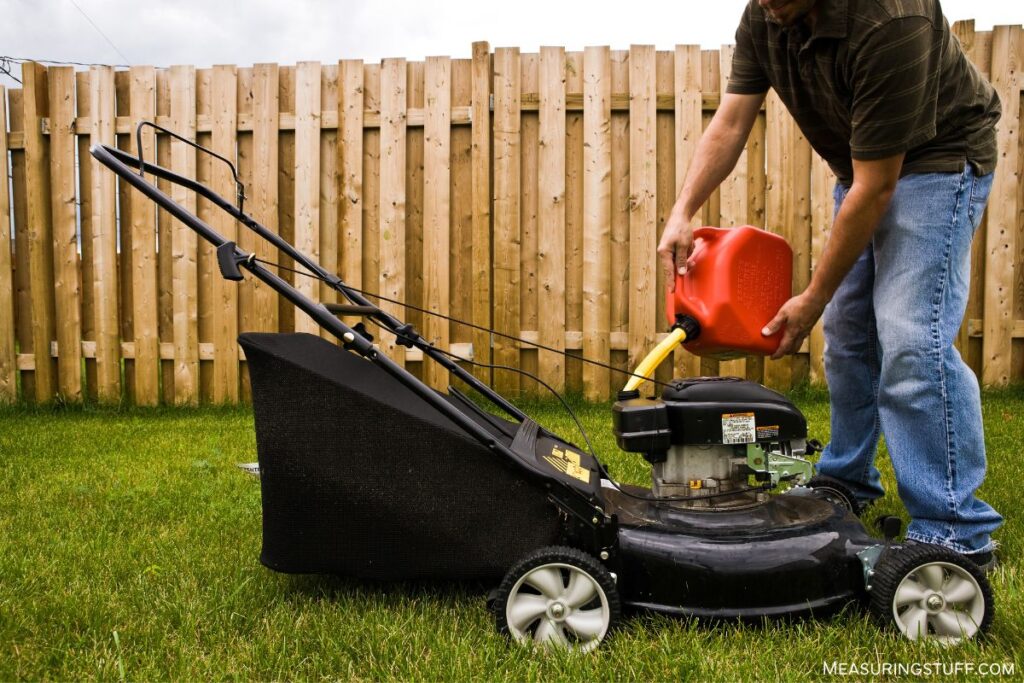 man pouring gas into a lawn mower