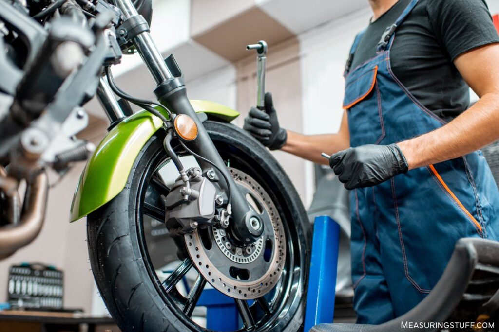 man performing maintenance on motor bike tire and brakes
