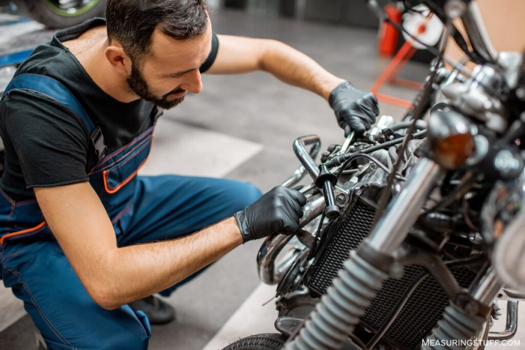 man performing engine maintenance on motor bike